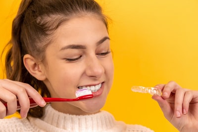 微笑的白毛衣女孩拿着红白相间的牙刷